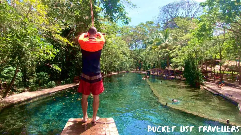 Man on rope swing platform at Ojo de Agua Ometepe Island Nicaragua