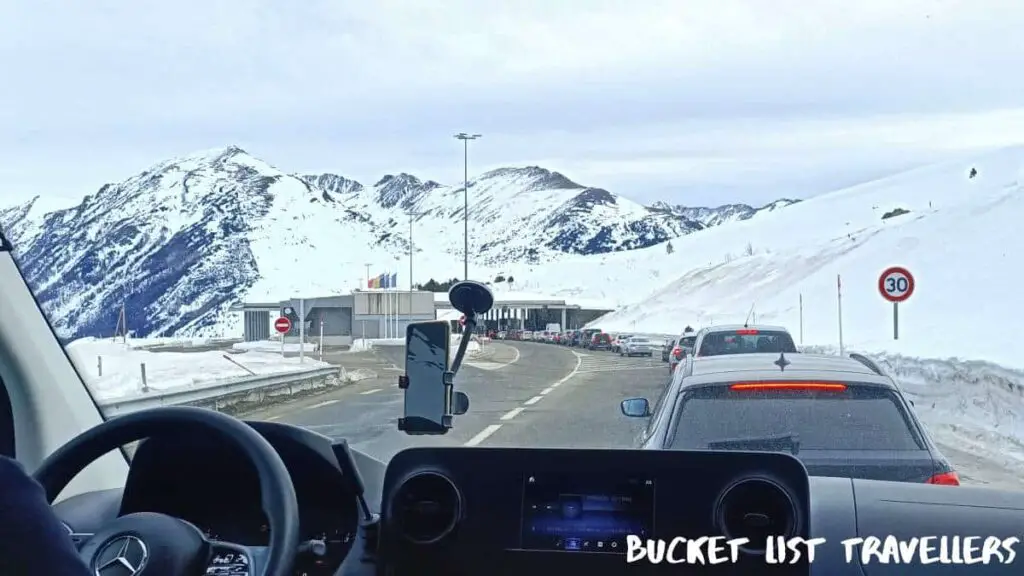 Andorra to France Land Border Crossing by bus, queue of vehicles at the French border crossing, snow capped mountains in the background