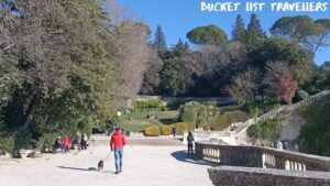 Man in red jacket and jeans walking dog at Jardin de La Fontaine Nîmes France