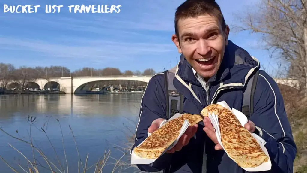 Man looking excited and holding 2 Crêpes from Jean Le Gourmand Crêperie Avignon France, Rhône River and Pont d'Avignon