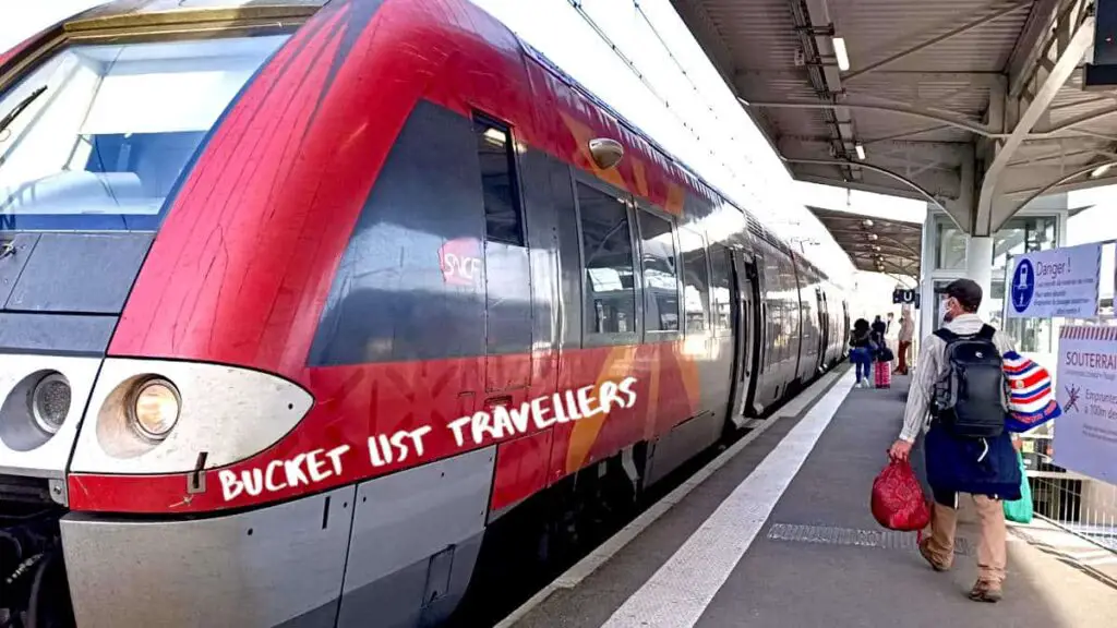 TER Train from Toulouse to Carcassonne France, red train, man walking on train platform carrying bags and wearing a mask