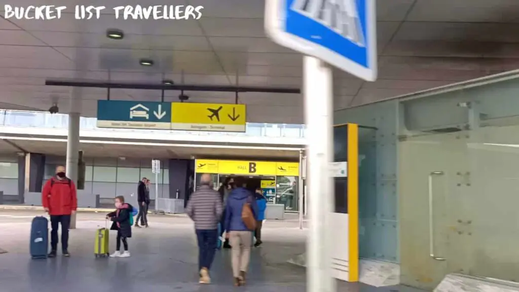 Entrance to Hall B at Toulouse Airport, People in masks with luggage