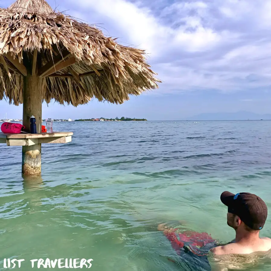 Man sitting in the water at Chepes Beach Utila Honduras