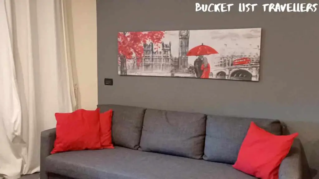 Airbnb Genoa Italy, grey couch with red cushions, red white and grey print of London on the wall