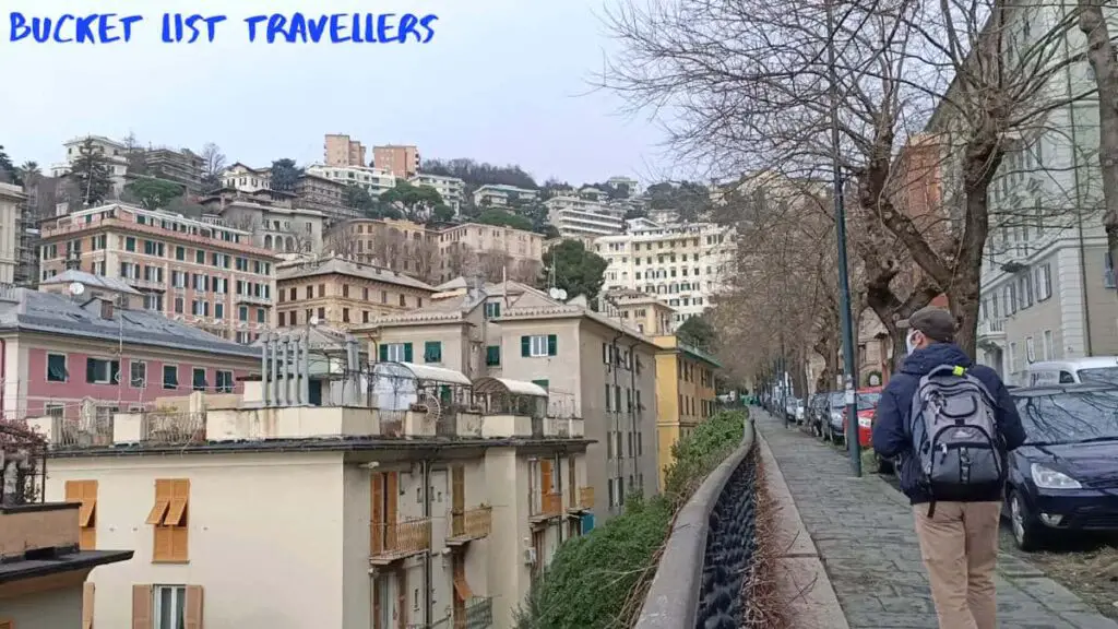 Man Walking in Genoa Italy, multilevel apartmentse and a row of cars parked on the street