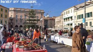 Market at Piazza Colombo Sanremo Italy, sunny Italian courtyard filled with people shopping at open air market