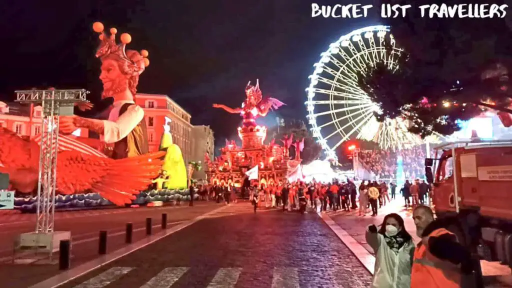 Nice Carnival Parade France, red lights, ferries wheel in white light, crowd of onlookers