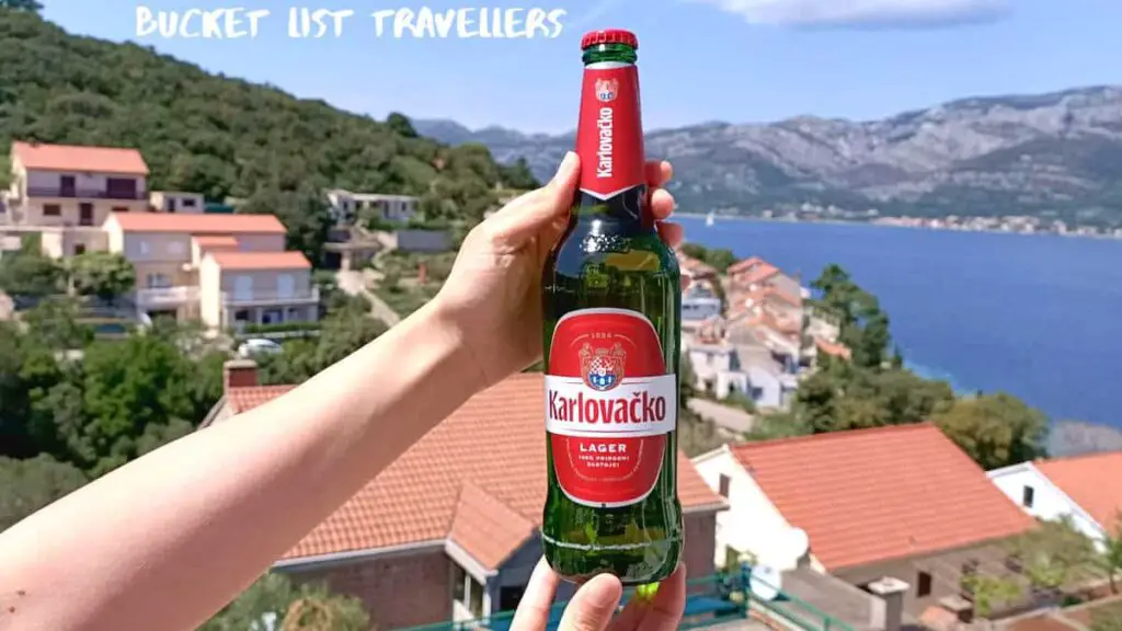Hands holding Karlovačko Beer with waterview of Korcula Croatia