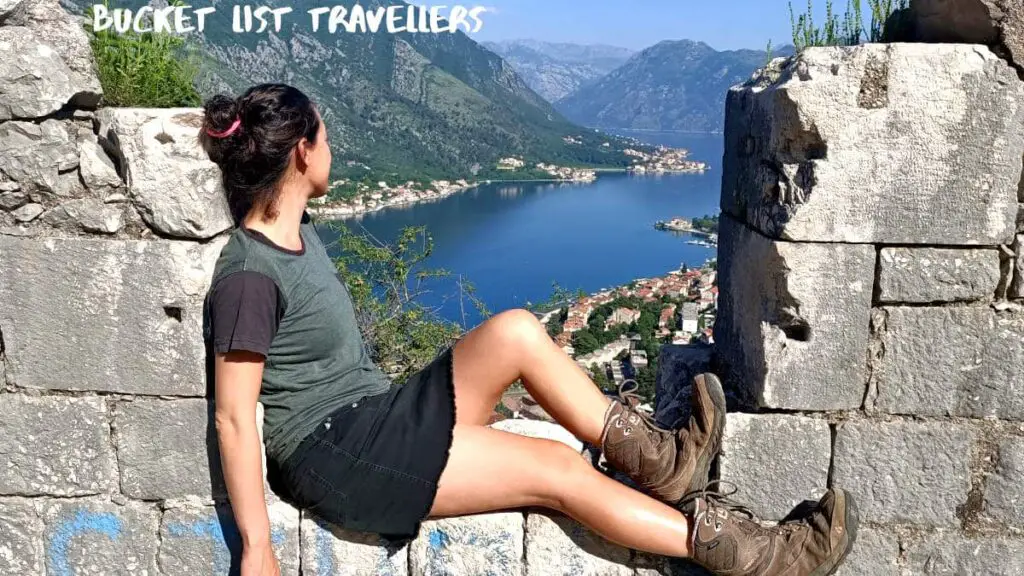 Woman Sitting on Wall of Ruins over Kotor Montenegro on road to the Fort of St Ivan