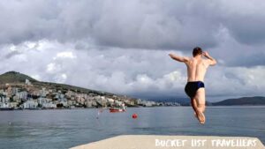 Man jumping off concrete platform into the water at Saranda Beach Albania