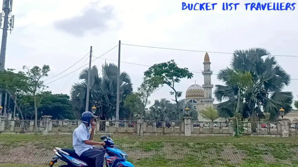 Man riding blue motorcycle near Masjid Sultan Ahmad Shah Al-Haj mosque Pekan Pahang Malaysia