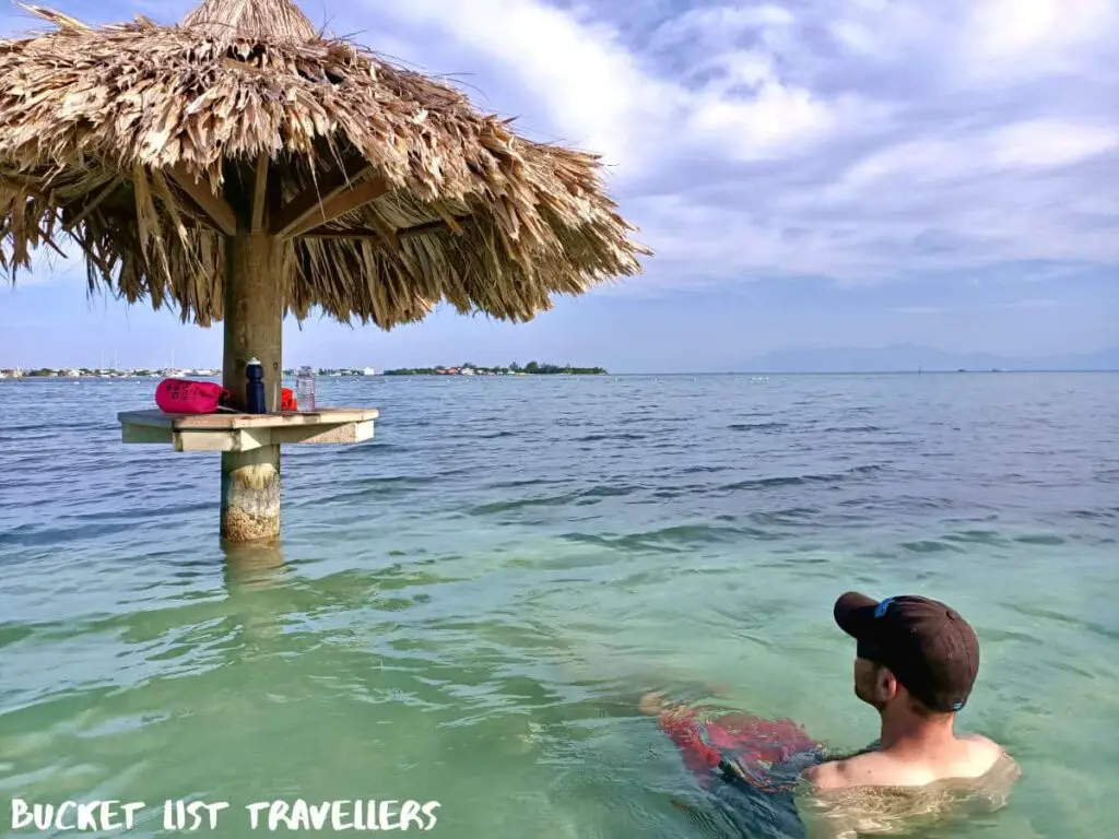 Man sitting in the water at Chepes Beach Utila Honduras