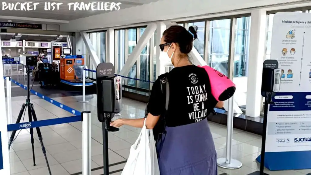 Woman disinfecting her hands with hand sanitiser at the entrance to Juan Santamaría International Airport San Jose Costa Rica