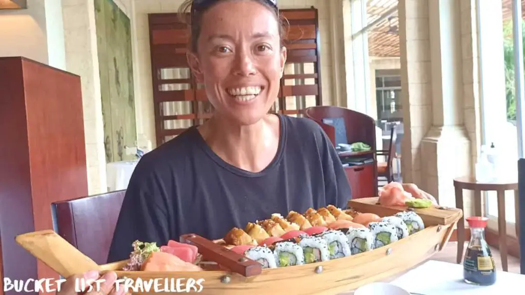 Woman in black t-shirt smiling and holding a sushi boat at Nau Lounge Real InterContinental Managua Nicaragua
