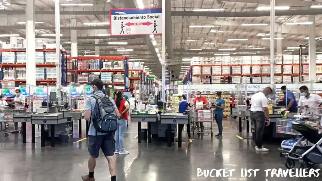 Checkout area at PriceSmart Managua Nicaragua; Social distancing sign; customers and staff wearing masks