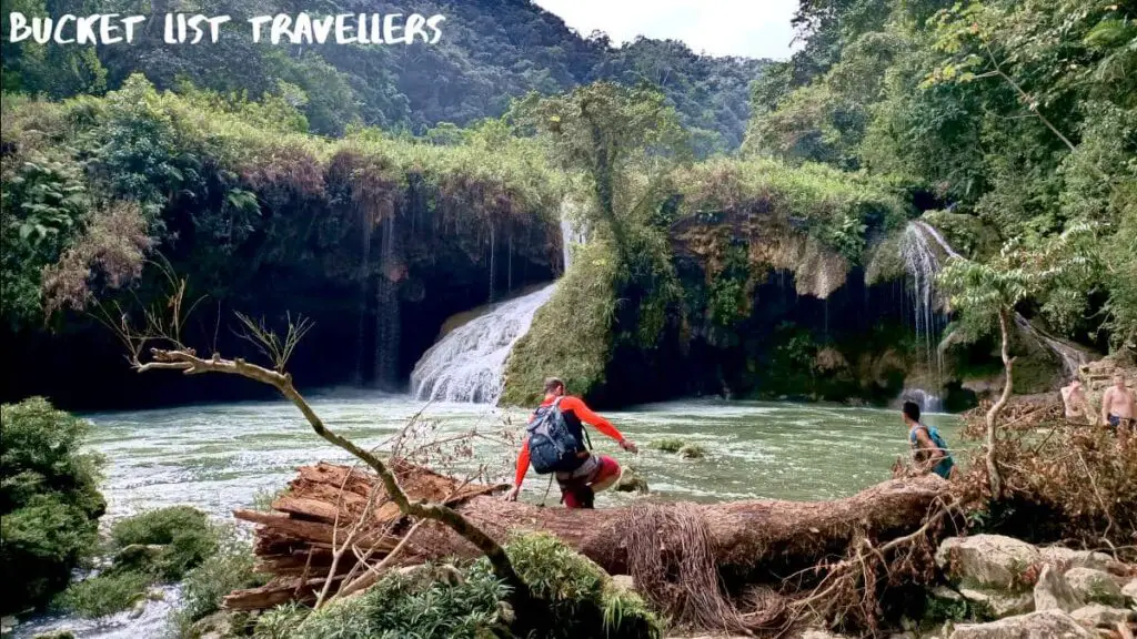 Semuc Champey Waterfall, Man climbing over fallen tree, pool at bottom of waterfall