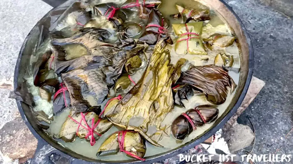 Pot of Nacatamales over hot stones - street food at Managua Nicaragua; food wrapped in banana leaves