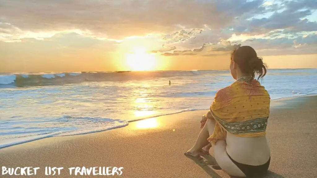 Woman sitting on Las Penitas beach at sunset Nicaragua